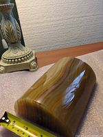 Oblique view of curved-top banded onyx bookend next to measuring tape showing length