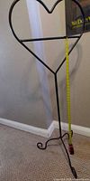 Full view of black heart-shaped metal floor stand showing overall form and height reference