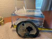 Agate slice in front of acrylic box with tape measure showing scale