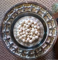 Top view of cast stone plate with glass vase filled with cream clay marbles