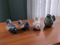 Four ceramic bird figurines/holders on table