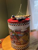 Ornament resting on tin lid showing size, colours, hanging string, and lid detail