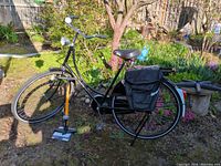 Full view of black Gazelle step-through bicycle with pannier bag and pump