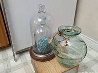 Cloche assembled on base beside blown glass vase