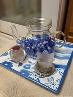 Lot overview showing pitcher filled with marbles, paperweight, votive on tray