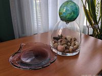 Cloche inverted with pebbles inside and sphere lid on top beside matching dish view