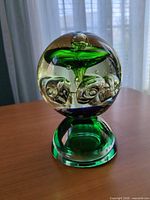 Full view of spherical paperweight on green glass base showing internal mushroom and bubble design
