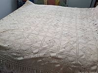 Full view of cream crochet afghan spread on bed