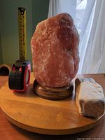 Front view of salt lamp with tape measure and extra stone on table