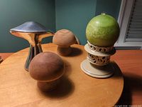 Lot overview showing aluminum mushroom, two wooden mushrooms, ceramic holder, green candle