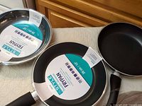 Three InStyle 10 in frypans with labels