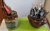 Stoneware crock and brown pot filled with flatware