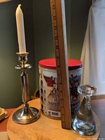 Metal candlestick, popcorn tin, glass candlestick with ruler for scale