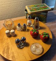 Group view of shakers, candle holder, tin, paperweight on wooden board