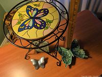 Full lot showing plant stand, ceramic butterfly dish, metal butterfly paperweight, garden plaque