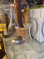 Group view of glass bottles, carafes, shaker, wooden rolling pins, wooden spoons in basket