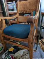 Front view of oak armchair showing carved crest and blue seat