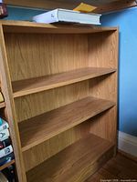 Full view of light oak veneer bookcase showing three shelves