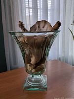 Seafoam glass vase containing driftwood and shells