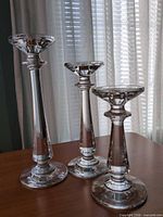 Three clear crystal candlesticks standing upright on table