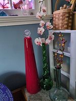 Red bottle-vase with stopper, green and clear vases grouped