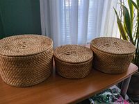 Three lidded seagrass baskets displayed side by side with lids on
