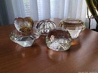 Four faceted crystal heart paperweights on table showing differing finishes