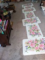 Row of seven floral vinyl placemats laid on floor