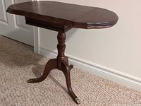 Full view of table with leaves up showing pedestal and brass feet