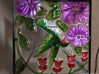Close-up of square glass top showing hummingbird and flower design