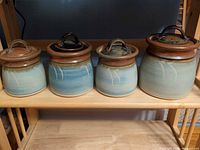 Front view of four blue speckled stoneware canisters with lids in place