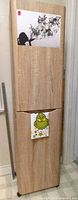 Front view of tall light oak cabinet with two doors and casters