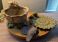 Group shot of ceramic planter, sunflower plaque, clip bird on table