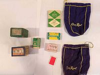 All items laid out: two Crown Royal pouches, multiple vintage staple and screw boxes, Ronson flints container