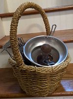 Wicker basket containing egg beaters, potato masher and disassembled food mill parts