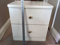 Front view showing two drawers, brass knobs and measuring tape indicating height