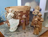 Front view of basket, angel figurine, and four corn husk dolls displayed on granite surface