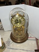 Full view of brass anniversary clock under glass dome