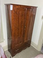 Front view of antique wooden wardrobe showing 2 doors and bottom drawer