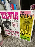 Both posters in plastic sleeves side by side showing overall designs