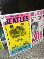 Beatles and partial Elvis posters side by side in plastic sleeves