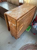 Closed table side view showing drop leaves and worn finish