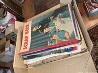 Box filled with stacked vintage magazines and newspapers