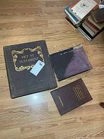 Three hardcover books laid on floor showing covers and size