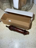 Full view of wooden whistle beside box