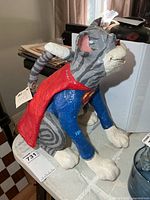 Full side view of signed Nancy Calder Superman dog sculpture on tabletop
