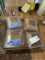 Four packaged hammered copper deck post caps on table