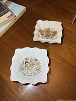 Both square scalloped dishes showing commemorative graphics