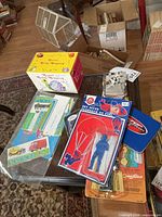 Overview of all items on table including boxed Disney toy, carded Sky Diver, sticker sheets, blue tin, booklets