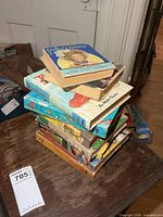 Stack of nine vintage hardcover books on table